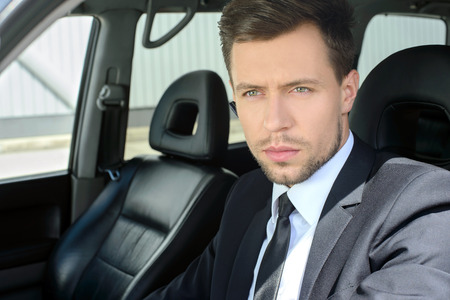 Young successful businessman riding in the carの写真素材
