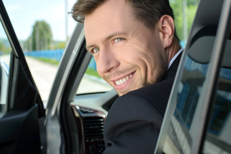 Young successful businessman riding in the carの写真素材