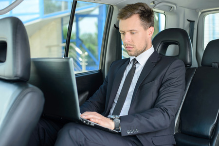 Young successful businessman riding in the carの写真素材