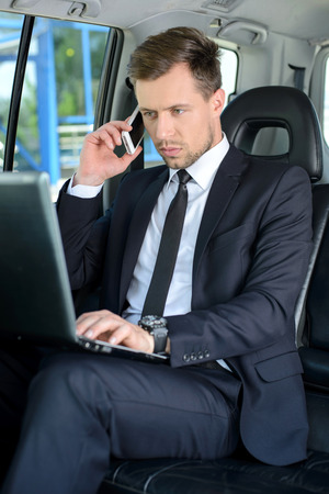 Young successful businessman riding in the carの写真素材