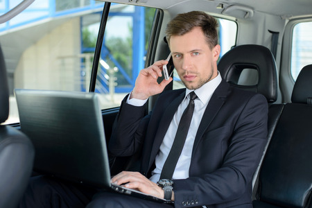 Young successful businessman riding in the carの写真素材