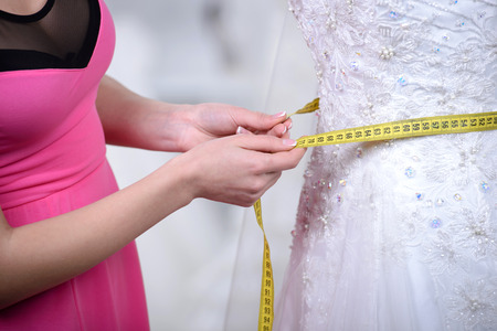 Designer wedding dresses, measures the dress on a mannequin in her shopの写真素材