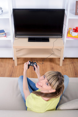Picture of happy woman with joystick playing video games at homeの写真素材