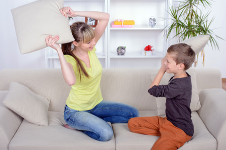 Funny Mother and Son battle the pillows on the couch at homeの写真素材