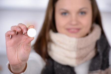 Woman taking aspirin. Young woman holding pill upon glass with water and expressing negativity while...