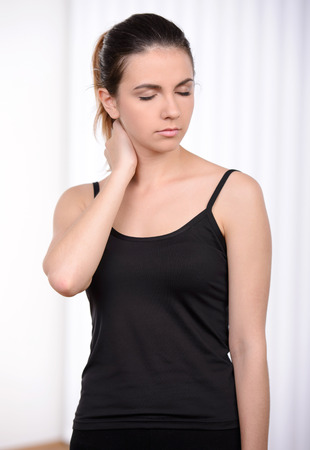 Feeling tired after workout. Tired woman in sports clothing holding hand behind head while standing in sport clubの写真素材