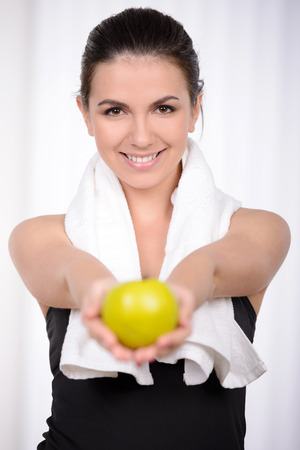 Living a healthy life. Beautiful woman in sports clothing throwing an apple up and smilingの写真素材