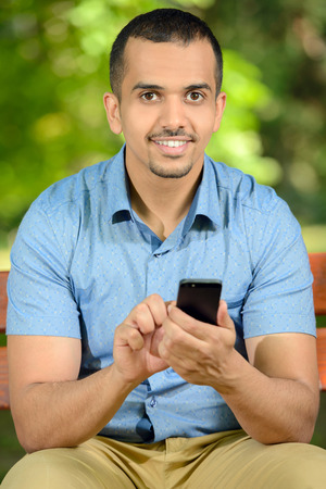 Young male student using a smartphone outdoors in parkの写真素材