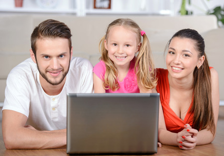 Family lying on floor at home using laptop at homeの写真素材