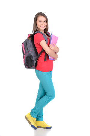 Portrait of teenager girl with school backpack holding colored folders isolated on white backgroundの写真素材