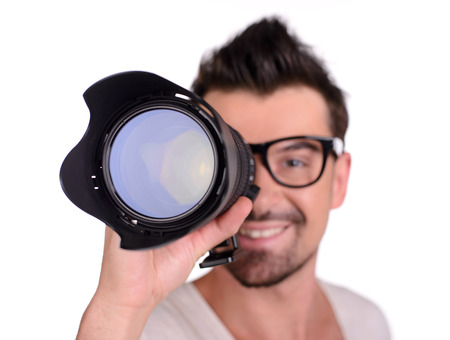Funny man photographer looking through the objective lens, isolated on white