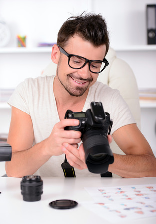 One man in white shirt is looking at photo in camera. Choosing photosの写真素材