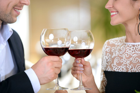 Young elegant couple drinking wine sitting in a restaurantの写真素材