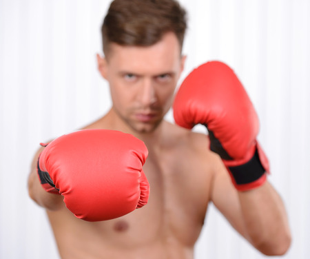 Always in great shape. Cheerful young muscular man boxer training in boxing glovesの写真素材