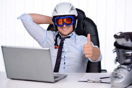Happy smiling business man in ski hamlet and mask. Happy about coming winter holidays and vocationの写真素材