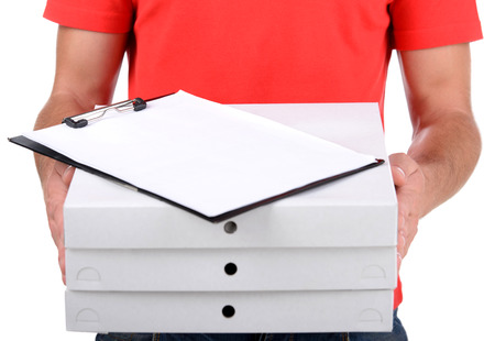 Cheerful young deliveryman holding a pizza box while isolated on whiteの写真素材