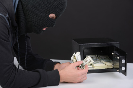 Thief burglar stealing money during home safe codebreakingの写真素材