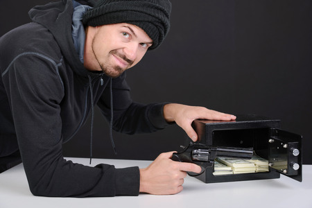 Thief burglar stealing money during home safe codebreaking
