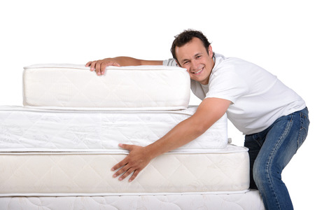 Funny man in pajamas sitting on lots of mattresses, isolated on white backgroundの写真素材