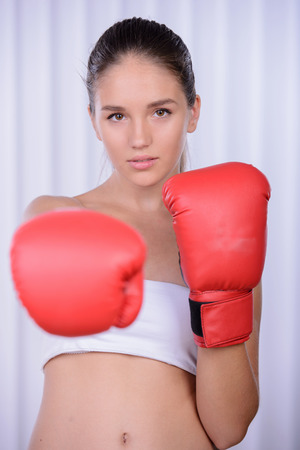 Beautiful woman with the red boxing gloves, white backgroundの写真素材
