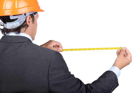Businessman in a helmet with a meter in his hands. White background