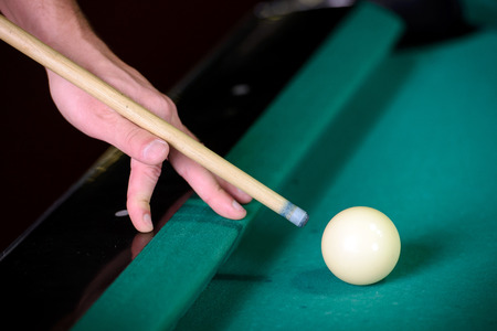 Billiards. Billiard balls on green table and white ball on the foreground. Hand of someone who is playing pool.の写真素材