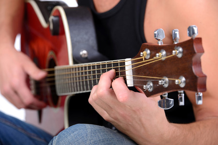 Young musician playing guitar, isolated on white