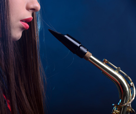 Saxophonist woman in red dress. Smoke backgroundの写真素材