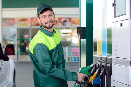 Smiling worker at the gas station, while filling a carの写真素材