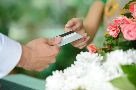Young woman working as florist giving credit card to customer after purchase.の写真素材