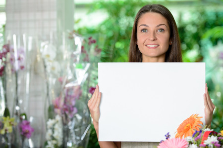 Young smiling woman florist working in the greenhouse.の写真素材
