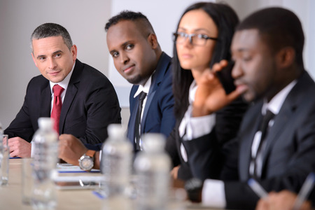 Business conference. Business meeting. Business people in formalwear discussing something while sitting together at the tableの写真素材