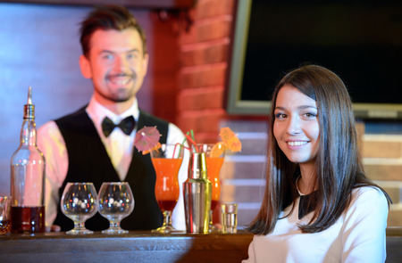 Handsome bartender serving cocktail to attractive woman in a classy barの写真素材