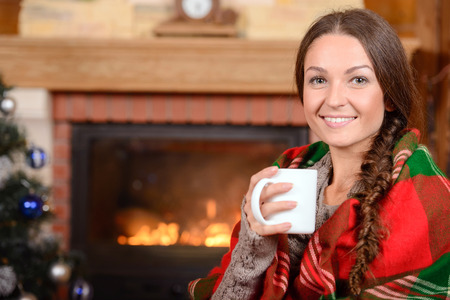 Young woman near fireplace in Christmas decorated house interiorの写真素材