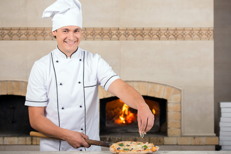 Chef baker in white uniform is making pizza at the kitchen.の写真素材