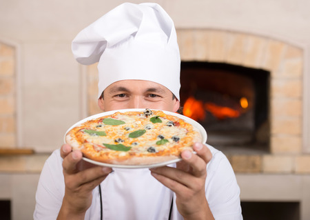 Young chef with neapolitan pizza margherita. Close-up.の写真素材