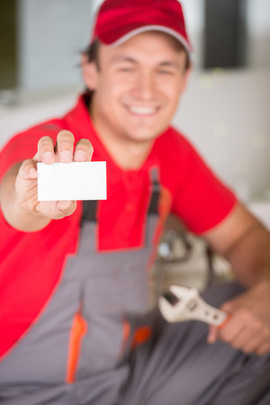 Plumber holding a spanner in hand and showing business card.の写真素材