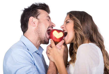 Happiness, health and love concept. Smiling couple with apple heart, isolated on white の写真素材