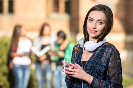 Young beautiful female student at the college, outdoors.の写真素材