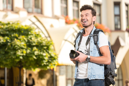 Portrait of happy young man, tourists with camera in the city.