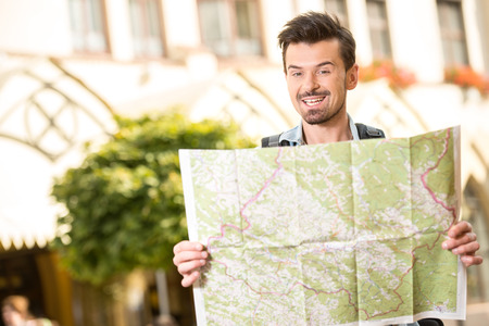 Trendy young man, tourists in the town with touristic map.の写真素材