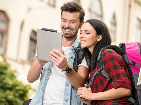 Young tourists are looking at the tablet in the town.の写真素材
