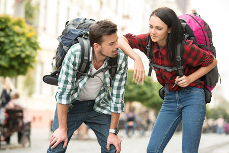 Two young tourists with backpacks are sightseeing city. Tired.の写真素材