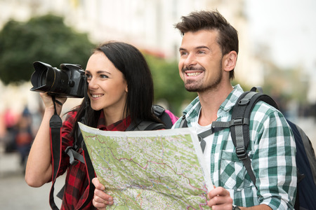 Two young tourists with backpacks, touristic map and camera. Sightseeing City.の写真素材