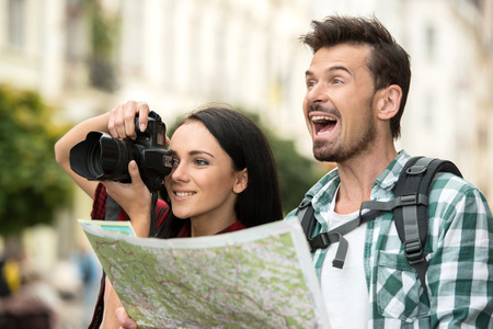 Two happy young tourists with backpacks, touristic map and camera. Sightseeing City.の写真素材