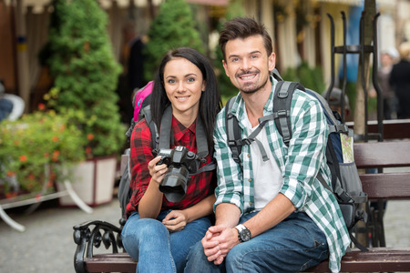 Young smiling couple tourists are walking in the city, looking at the camera.の写真素材