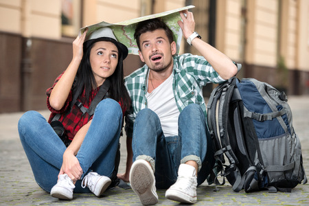 Young happy tourists is sitting on the ground. Sightseeing city with map.の写真素材