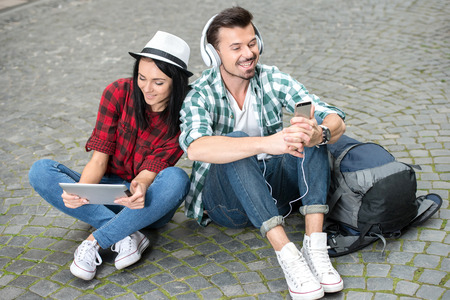 Young couple tourists with a tablet and headphones in the city.の写真素材