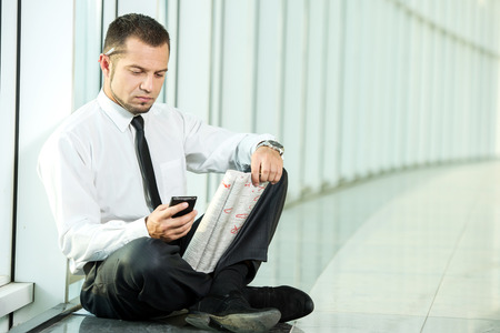 The concept of job search. A man is sitting with a newspaper and phone.の写真素材