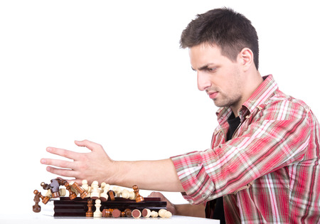 Young man is throwing chess from chess board on the white background.